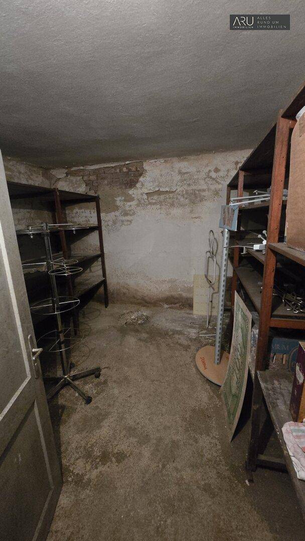 Weiterer Blick in den Kellerraum mit Regalen und unverputzten Wänden, ideal für Lagerzwecke.