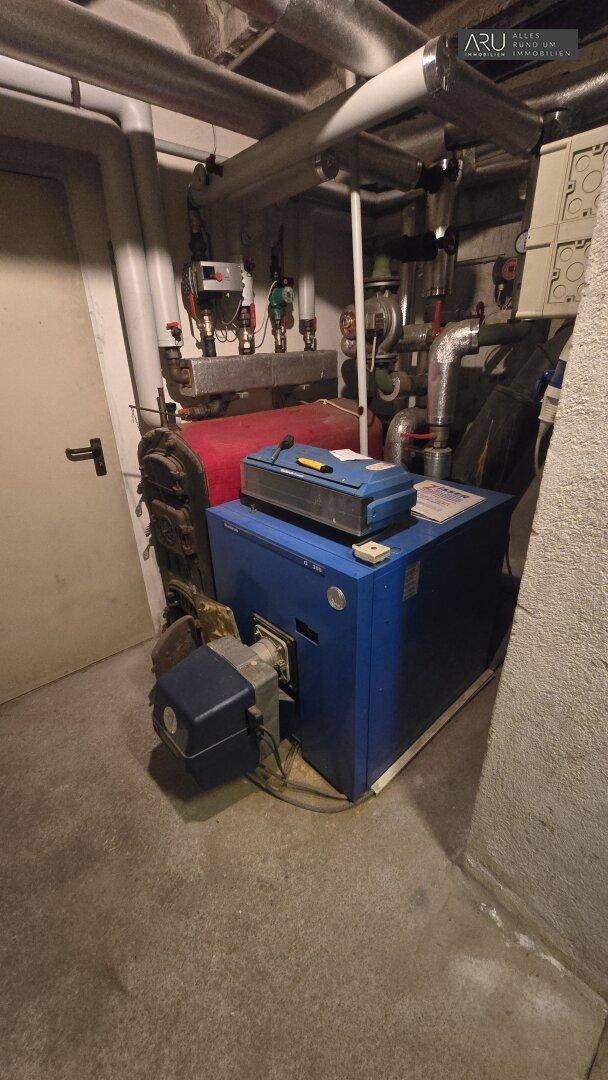 Heizungsanlage mit Kessel und Rohrleitungen in einem funktionalen Kellerraum.