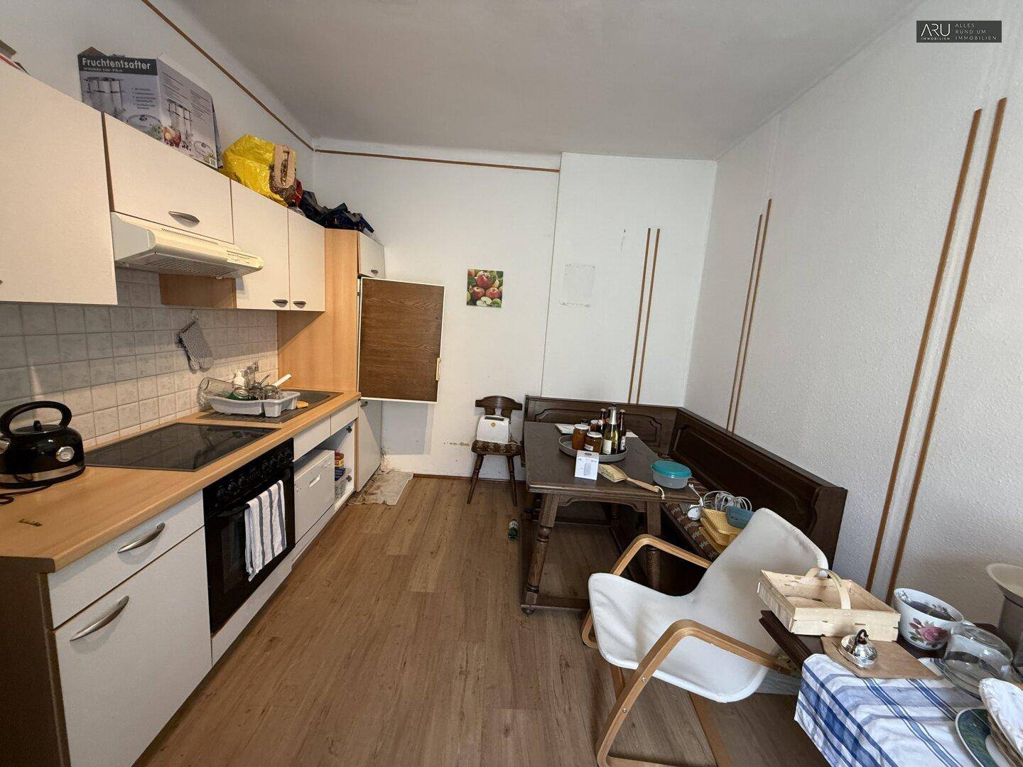 Einfache Küche mit Holztheke, Einbaugeräten und kleiner Essecke mit Sitzbank.
