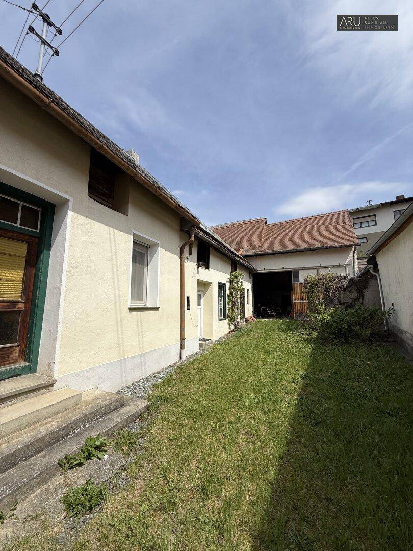 Schmaler Gartenbereich neben dem Haus mit Rasenfläche und einfacher Bepflanzung.