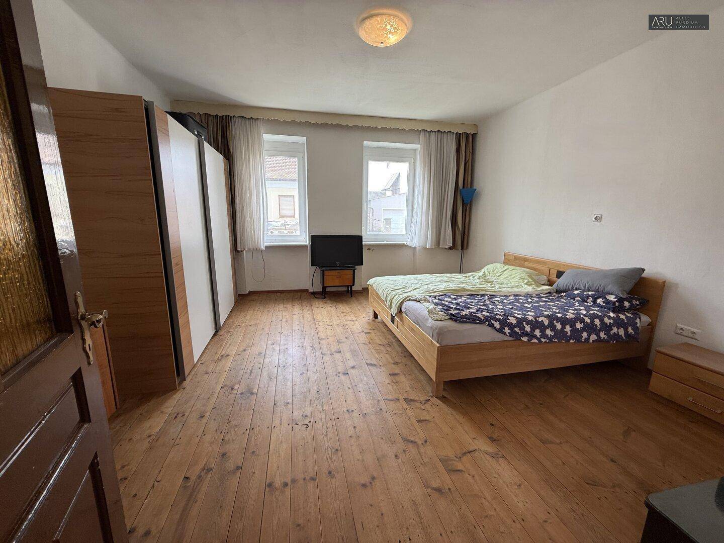 Schlafzimmer mit breiten Holzdielen, Doppelbett und großen Kleiderschränken.