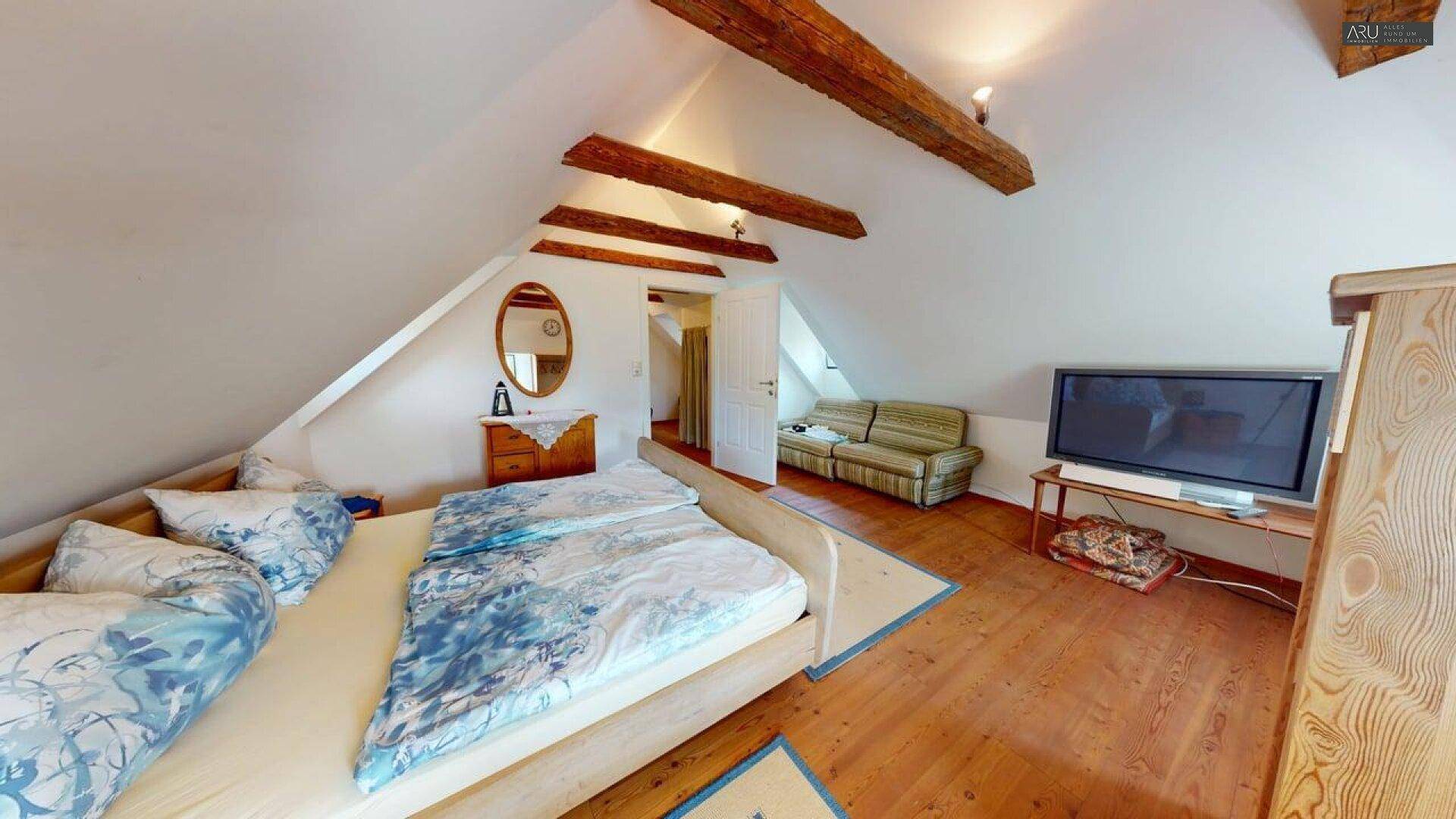 Geräumiges Dachgeschoss-Schlafzimmer mit Holzbalken, Holzboden und gemütlicher Atmosphäre, sehr hell.