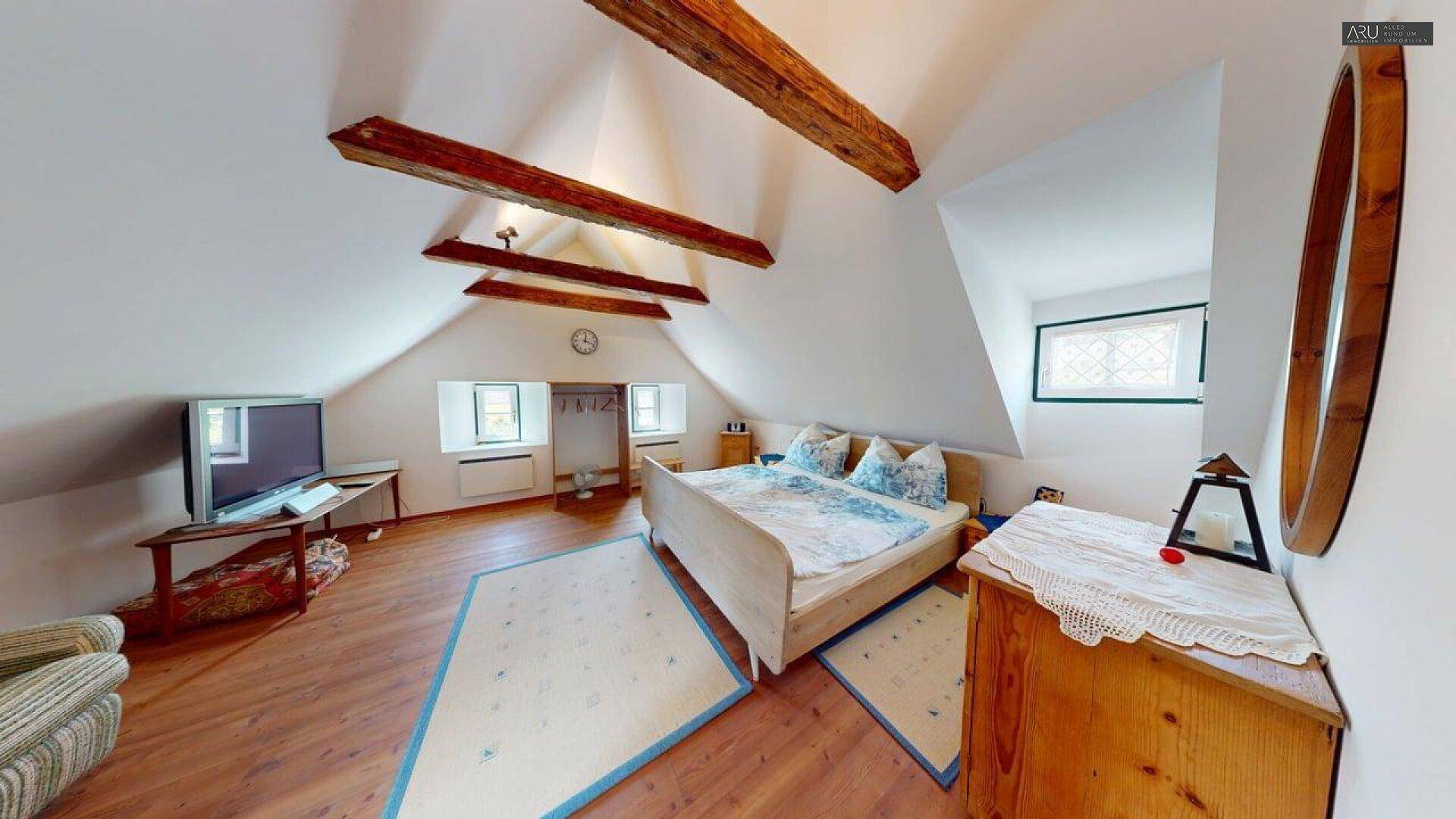 Dachgeschoss-Schlafzimmer mit sichtbaren Holzbalken, Holzboden und Dachschrägen, sehr gemütlich.