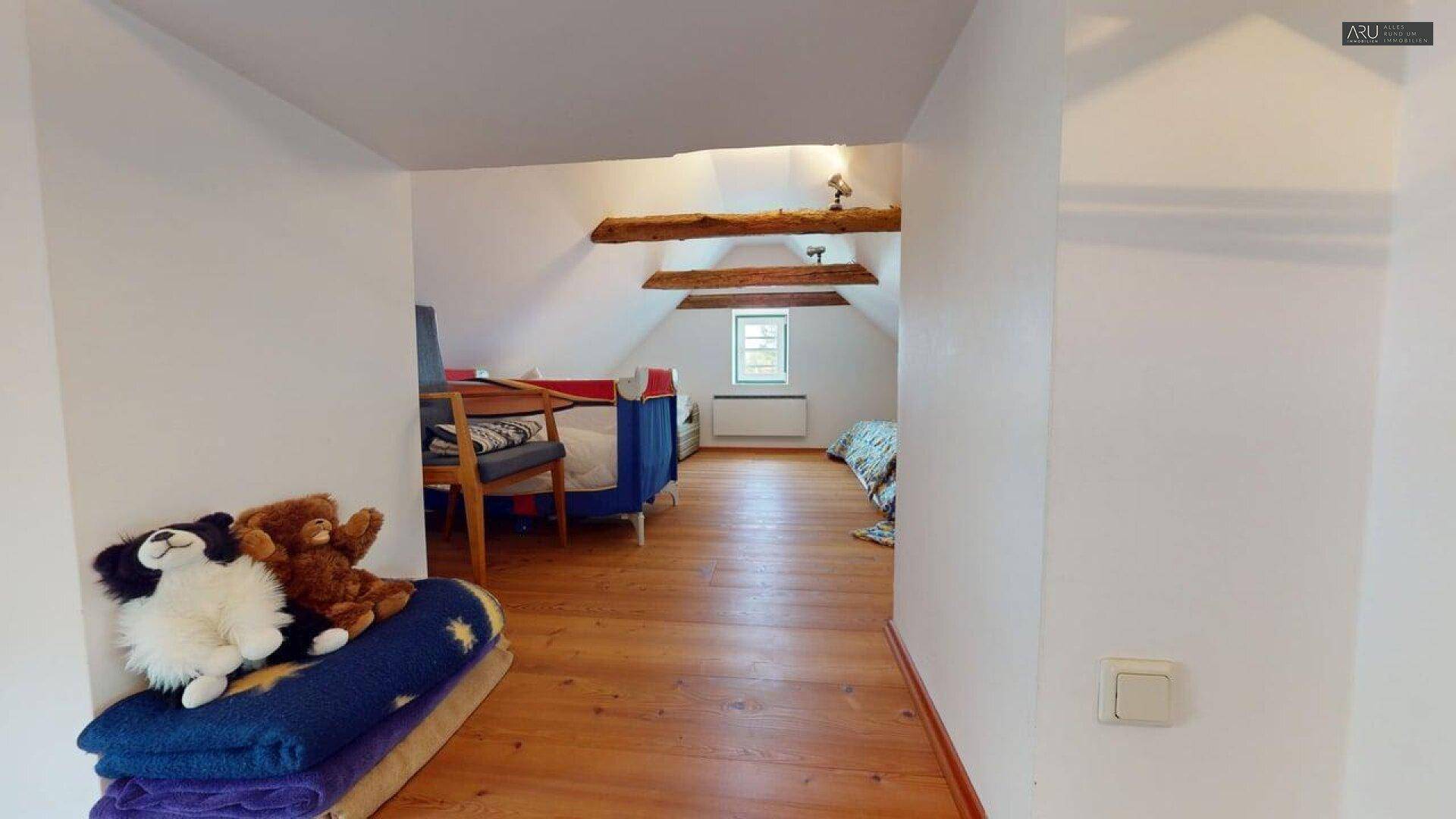 Dachgeschoss-Flur mit Holzboden und sichtbaren Holzbalken, verbindet die Schlafbereiche auf dieser Etage.