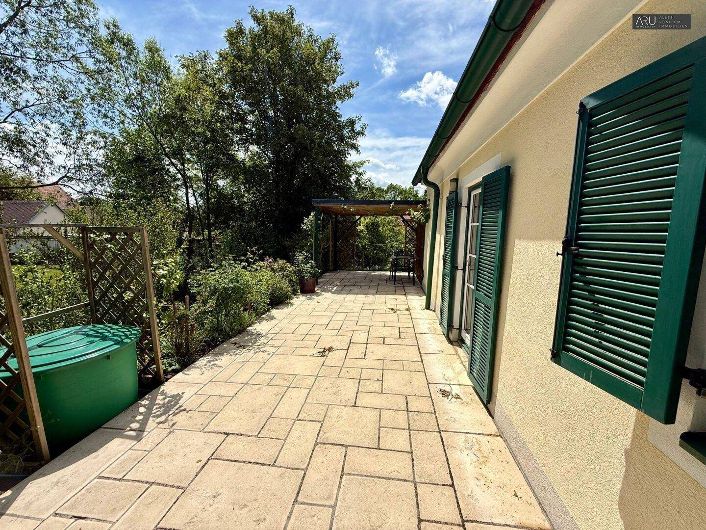 Gedeckte Terrasse mit Steinplattenboden und Blick ins Grüne, ideal für Entspannung im Freien.