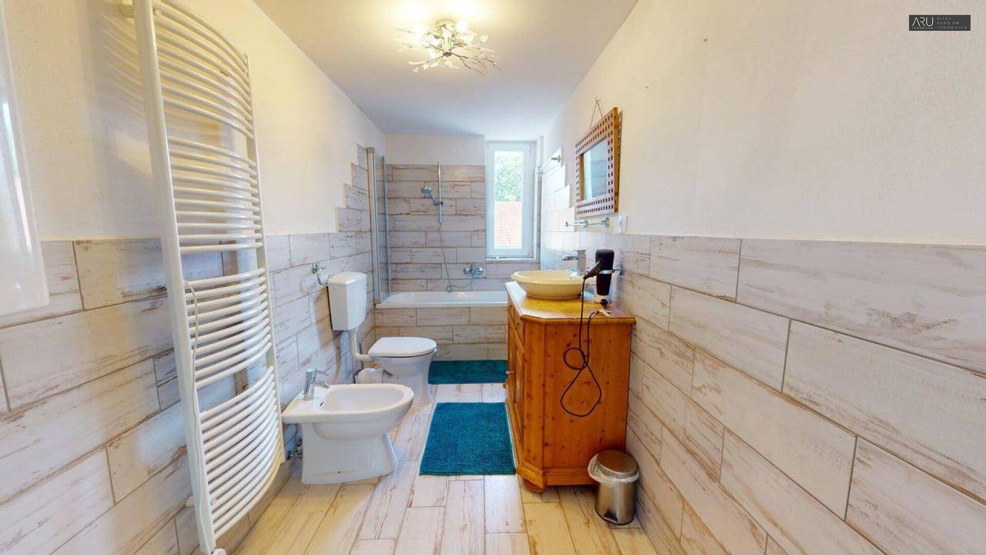 Badezimmer mit Holzfliesen, Waschtisch und beheiztem Handtuchhalter.