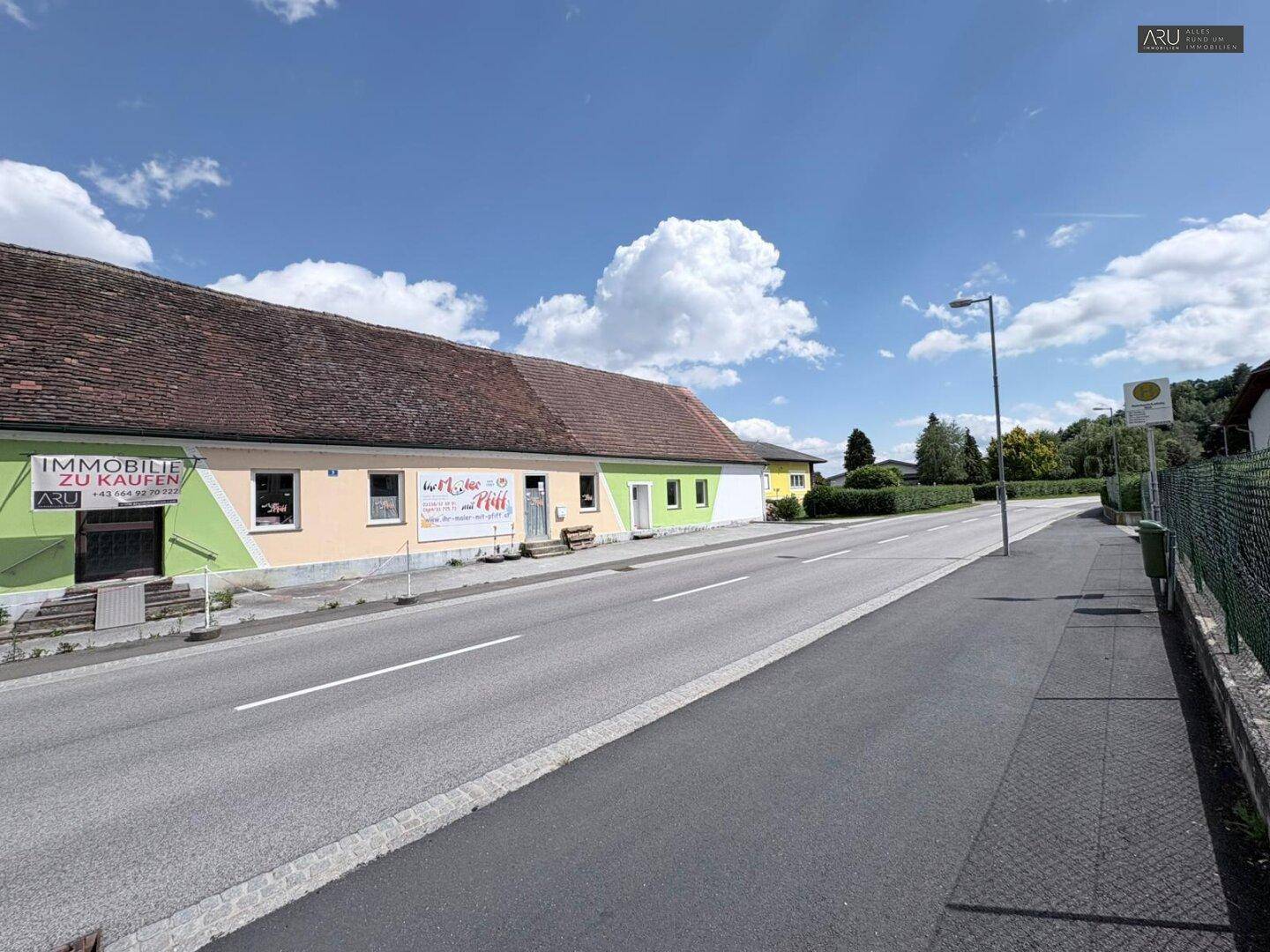 Ländliches Gebäude mit farbiger Fassade und Satteldach, direkt an einer Landstraße gelegen.