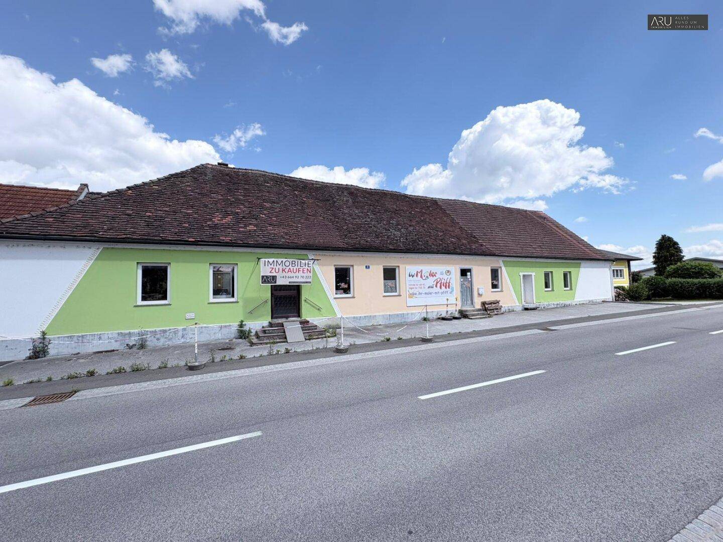 Lange Fassade des Gebäudes entlang einer Straße mit farbigen Anstrichen und Werbebannern.