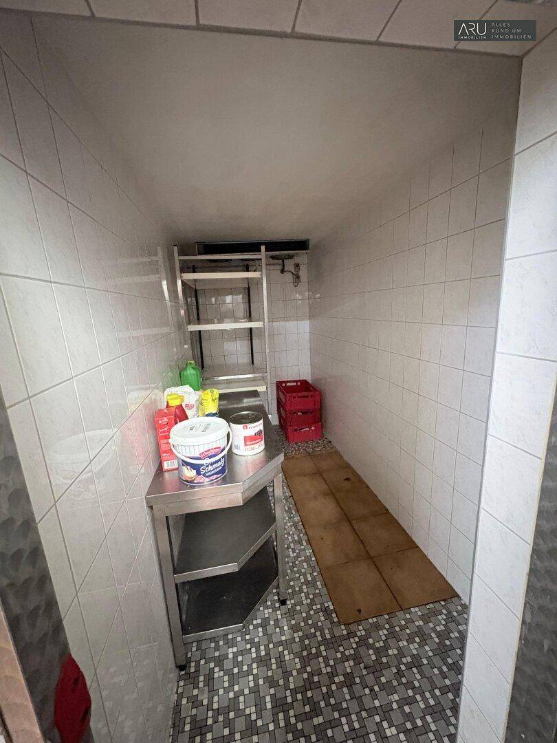 Kleiner Abstellraum mit gefliesten Wänden und praktischen Regalen für Lagerzwecke.