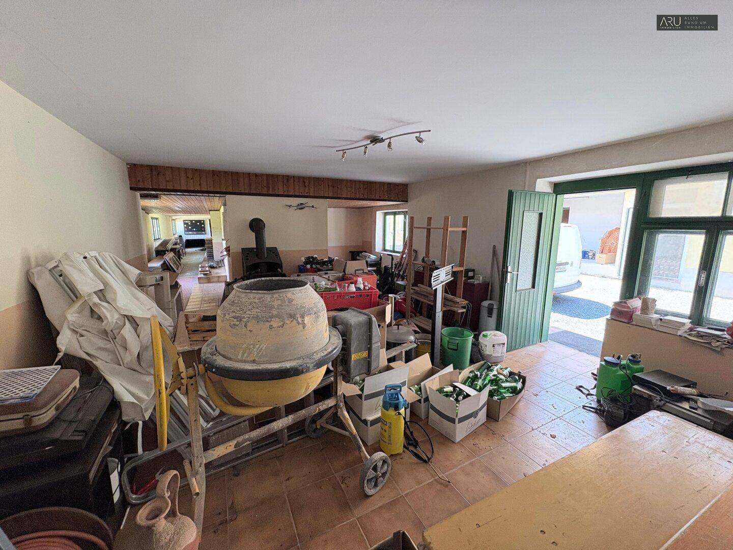 Großer, unaufgeräumter Raum mit Baumaschinen und Werkzeugen, ideal als Werkstatt oder Lager.