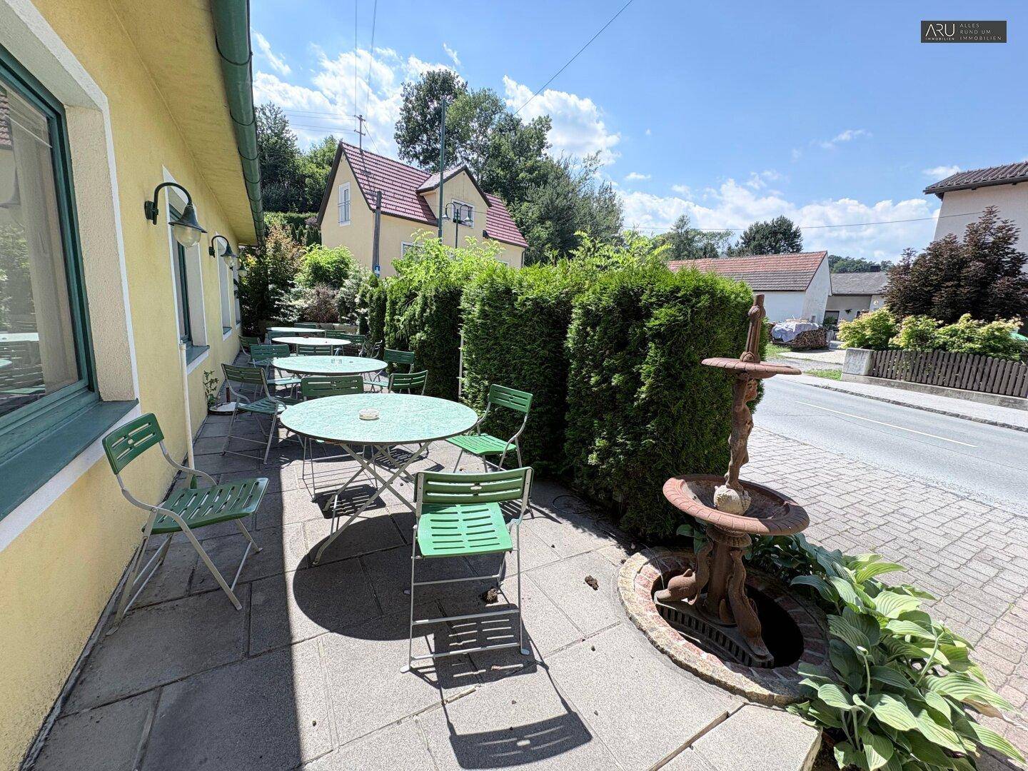 Gemütlicher Außenbereich mit Tischen und Stühlen, ideal für Gäste im Freien.