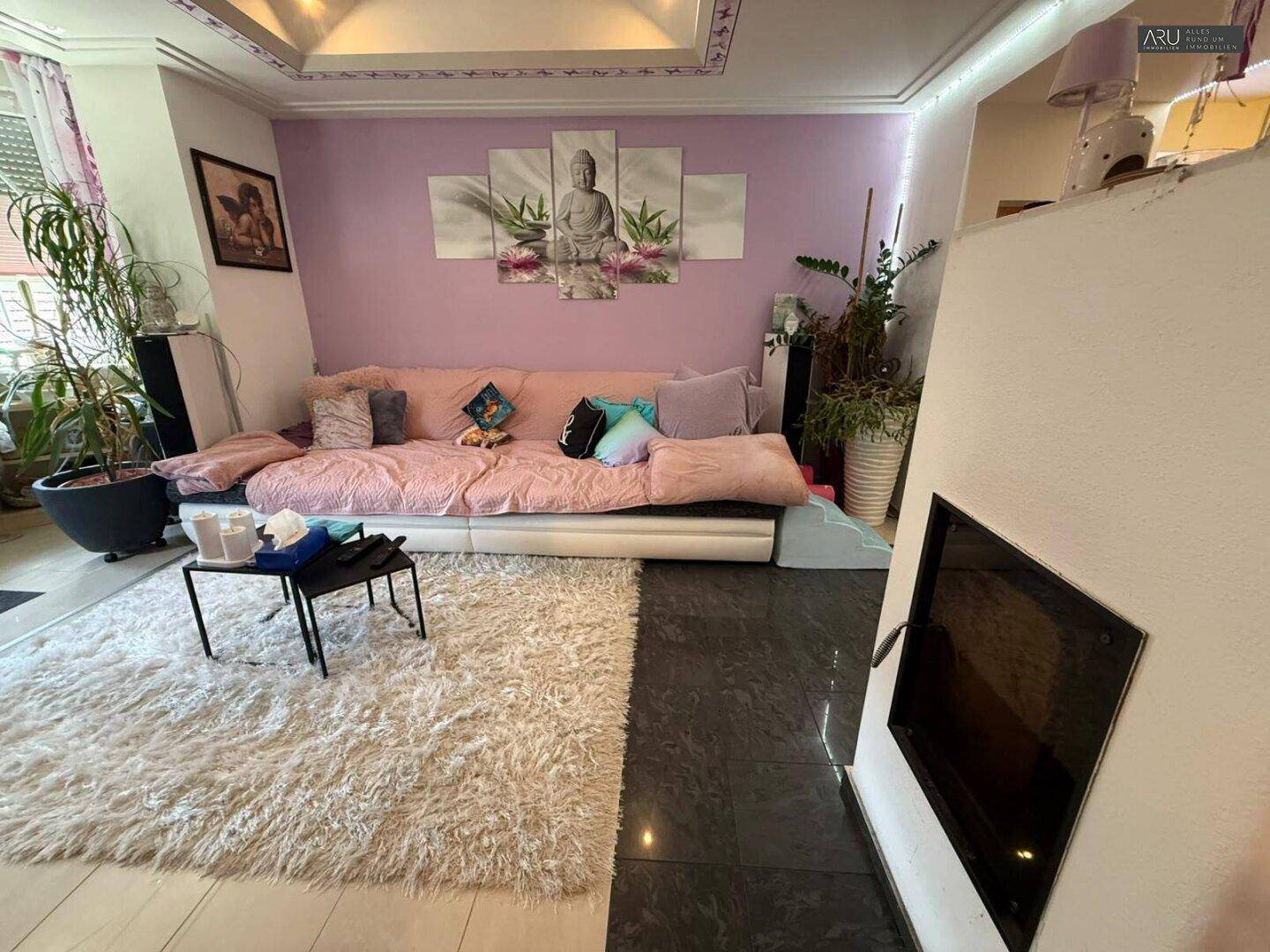 Wohnzimmer mit Kamin, großem Sofa und hellem Teppich.