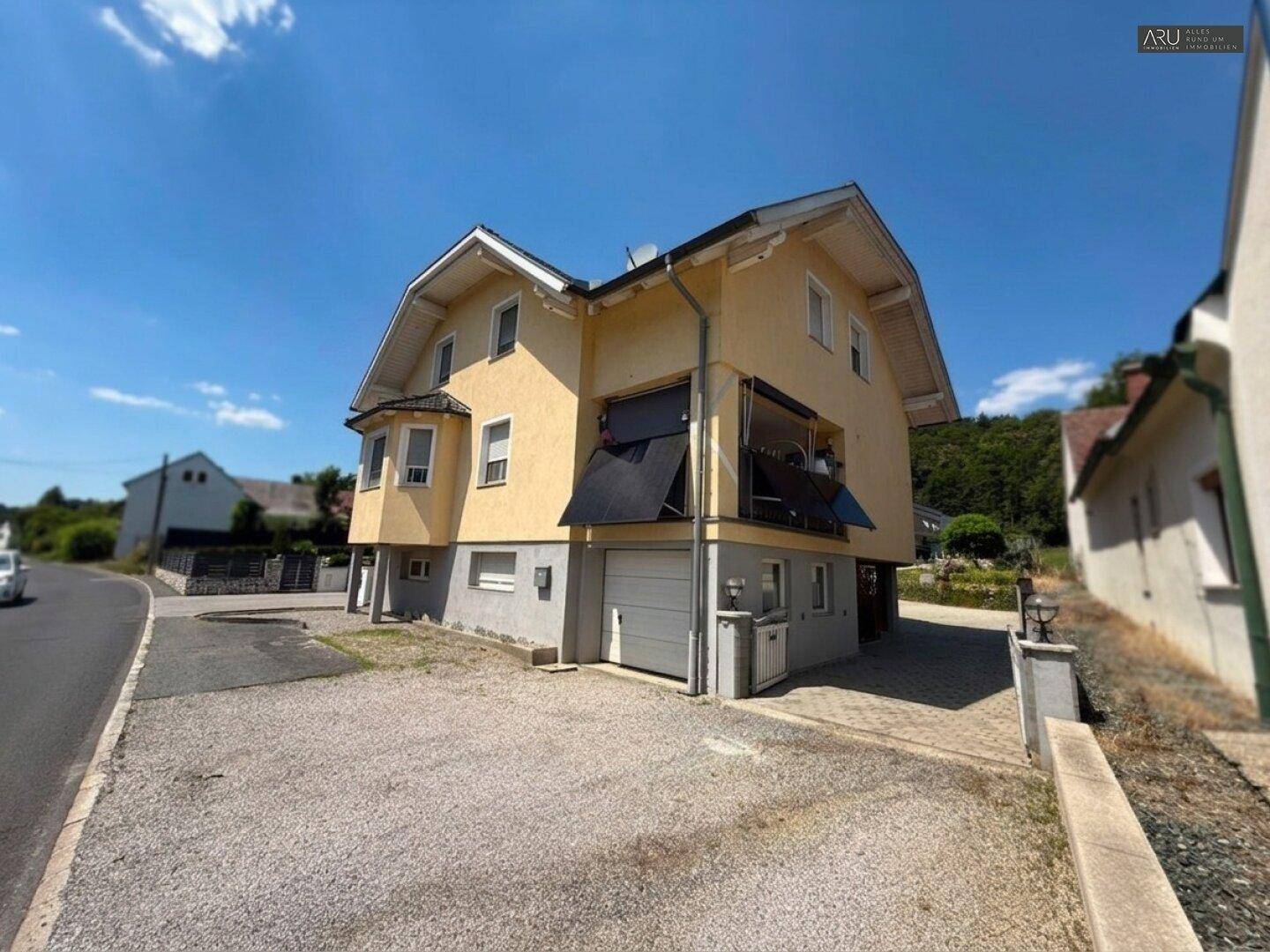 Freistehendes Einfamilienhaus mit Garage und Kiesauffahrt unter blauem Himmel.