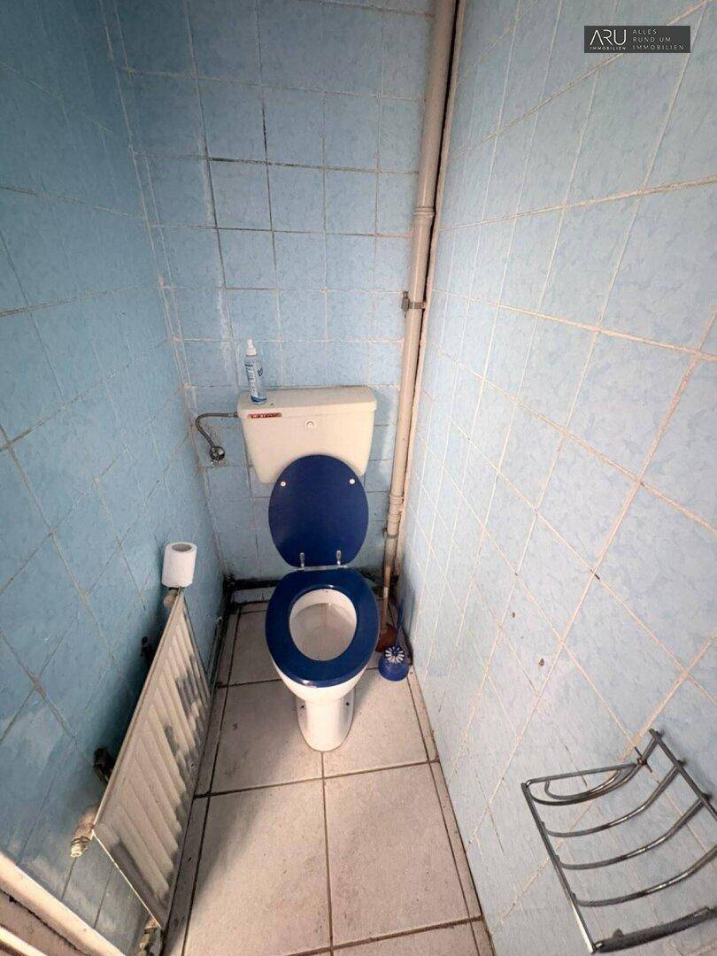Kleines WC mit blauen Fliesen und einer Toilette mit blauem Sitz.