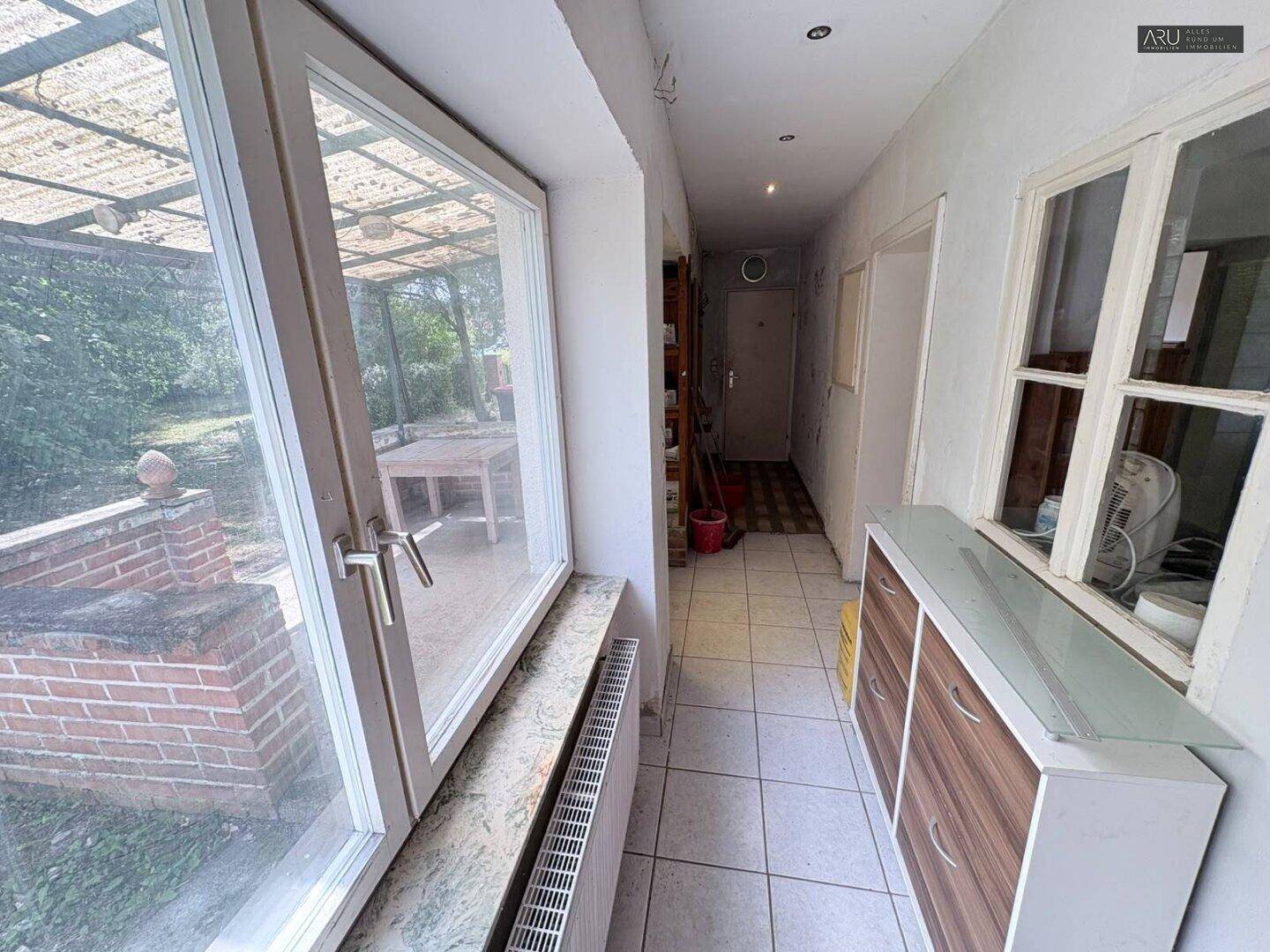 Heller Flur mit Fliesenboden und großem Fenster mit Blick auf den Außenbereich.