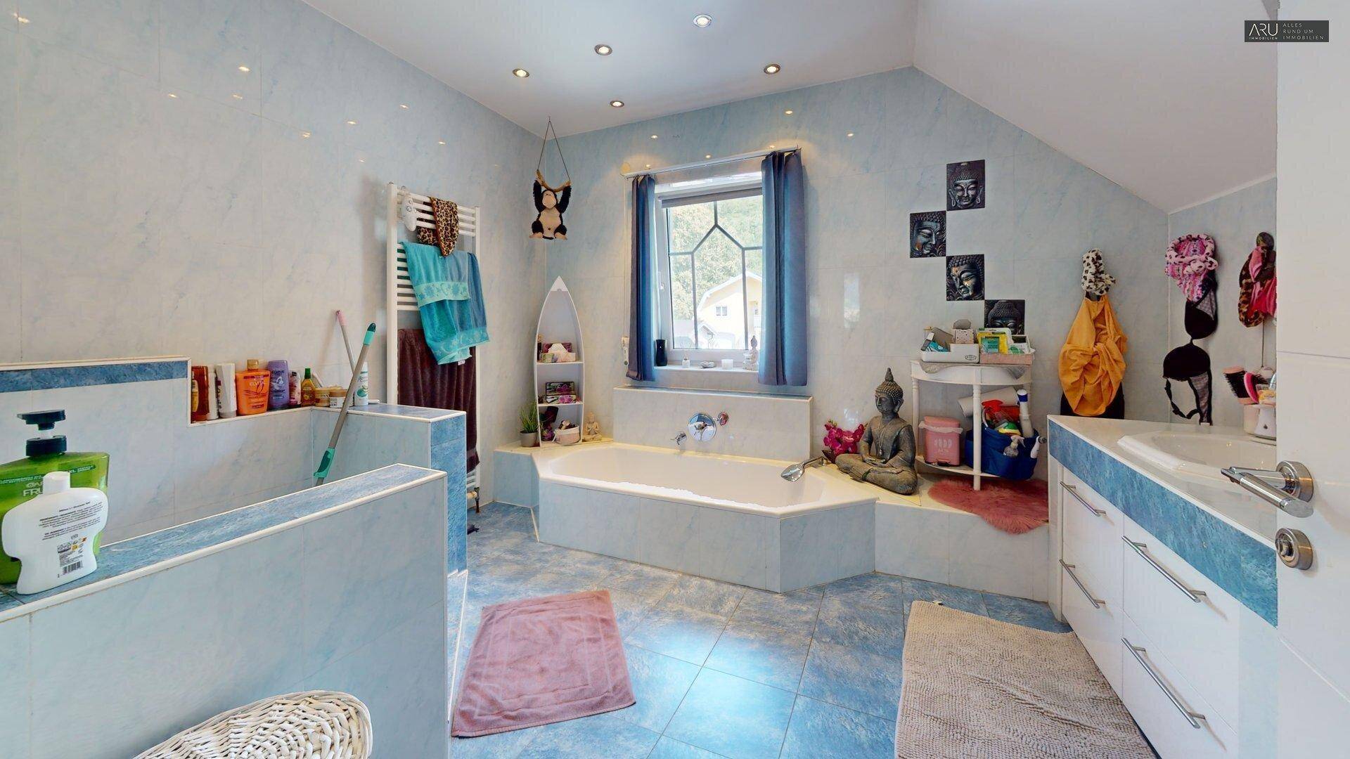 Geräumiges Badezimmer mit Eckbadewanne, Dusche und blauen Fliesen.