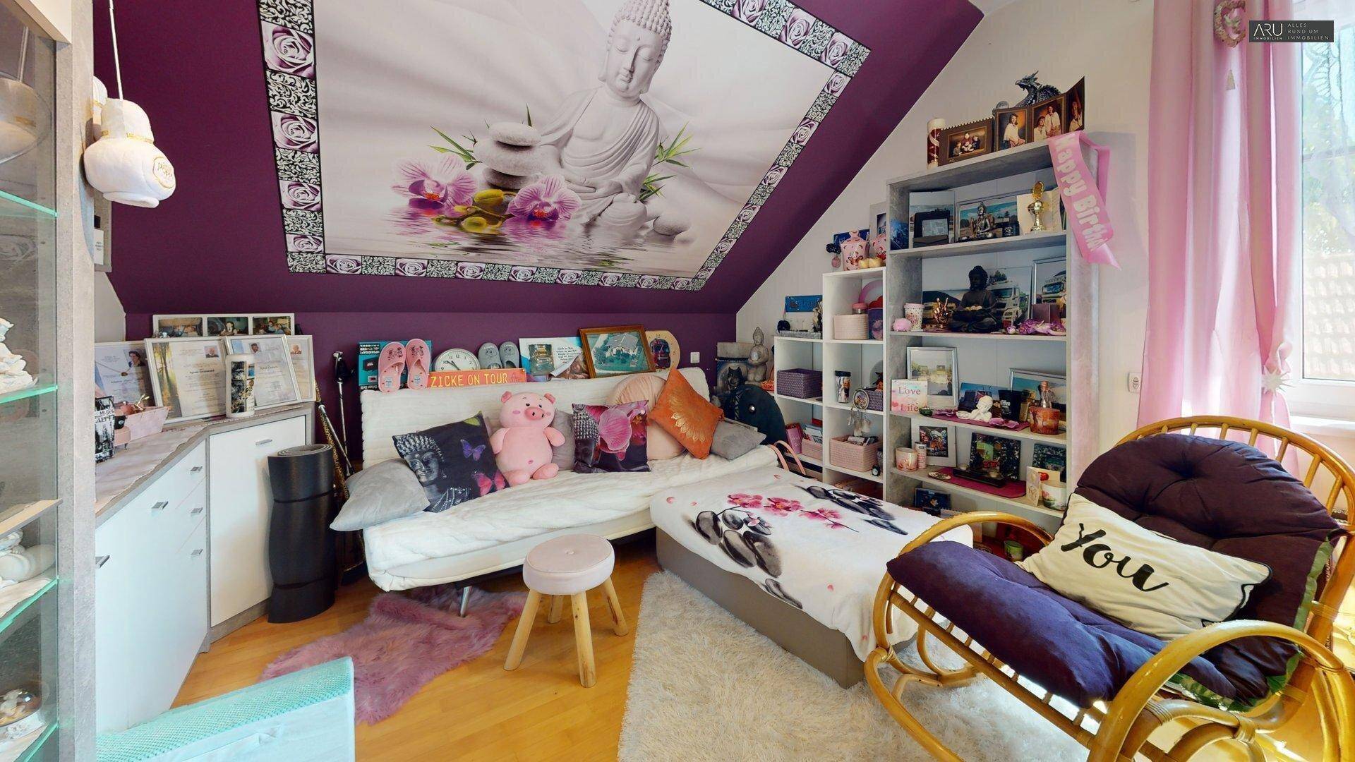 Gemütliches Schlafzimmer mit Dachschräge, vielen Regalen und Buddha-Dekoration.