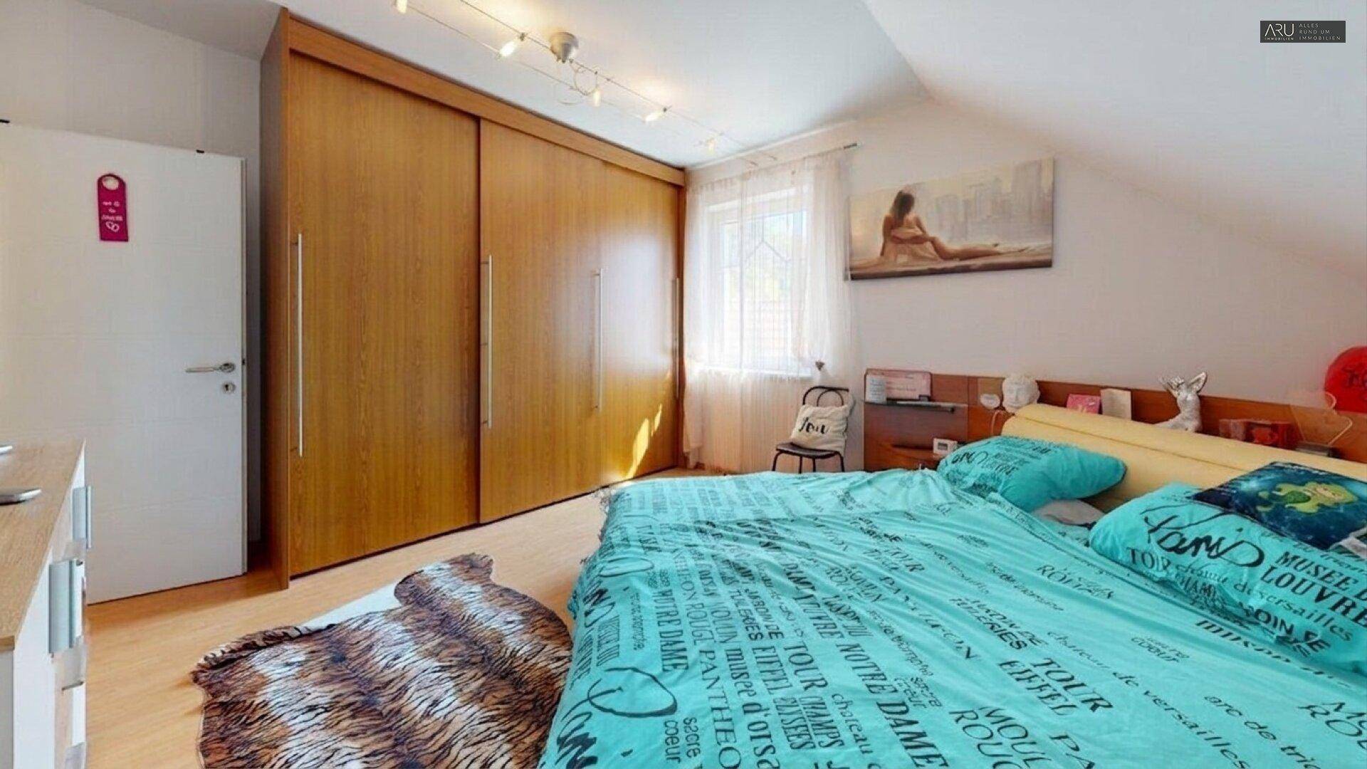 Schlafzimmer mit großem Einbauschrank, Fenster und Holzboden.