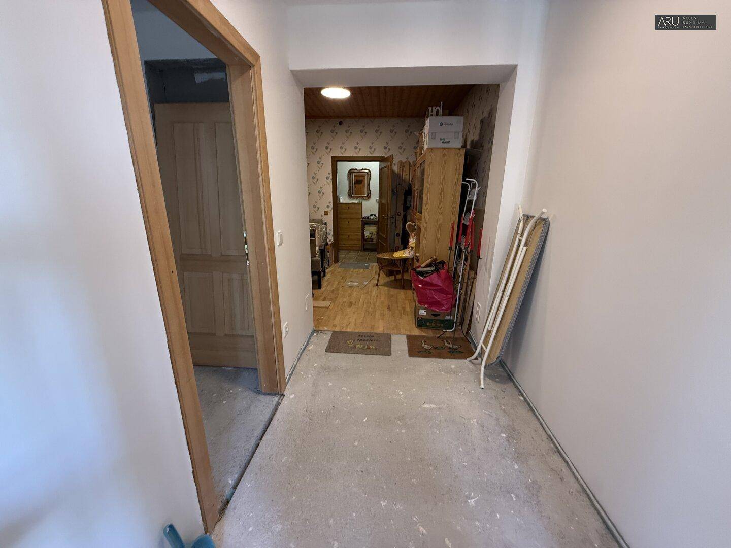 Heller Flur mit schlichten Wänden, der zu einem weiteren Raum führt.