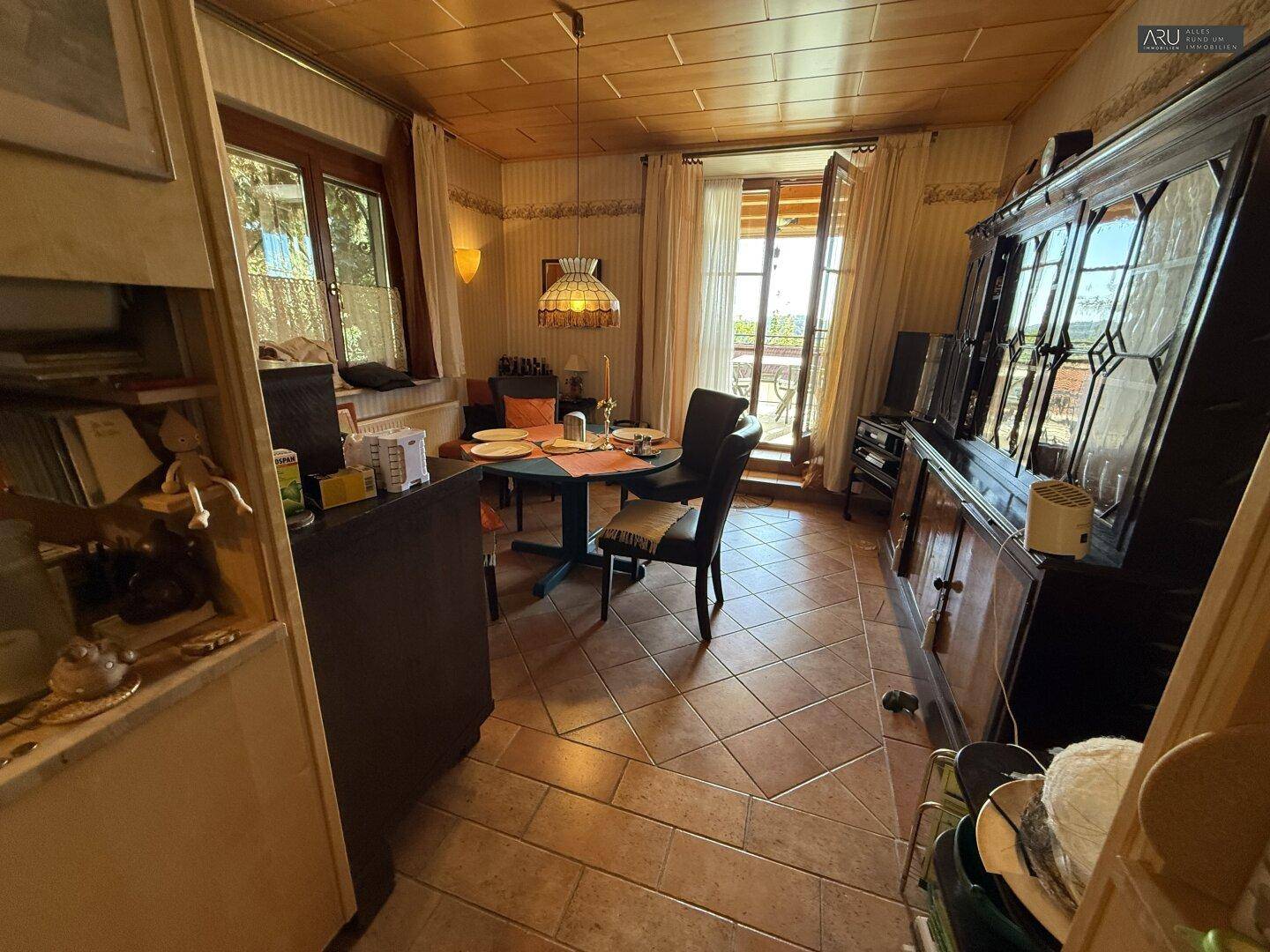 Gemütlicher Essbereich mit Zugang zum Balkon, Holzdecke und traditionellen Möbeln.