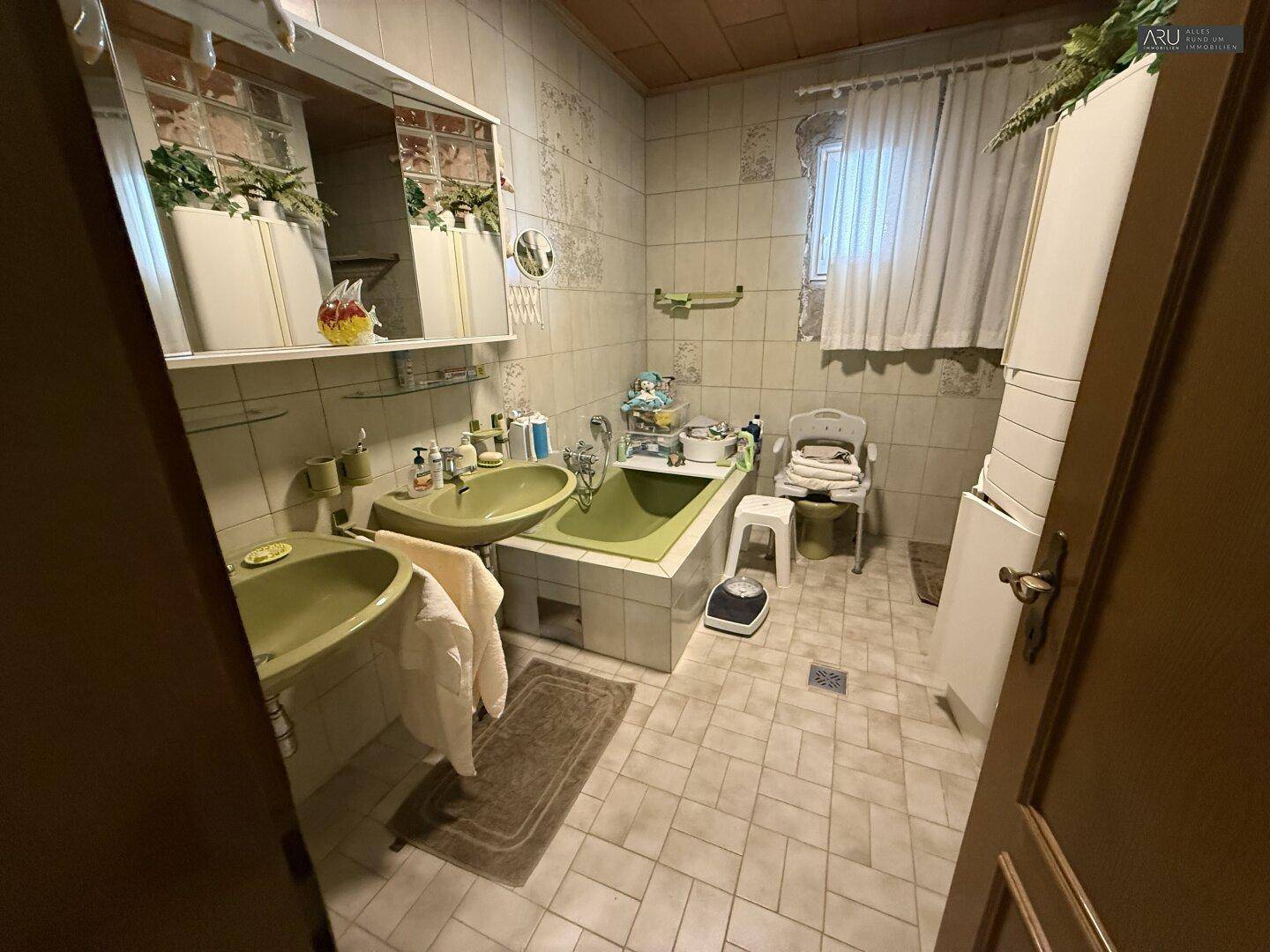 Badezimmer im Stil der 80er Jahre mit grünen Sanitärobjekten und Fliesen.