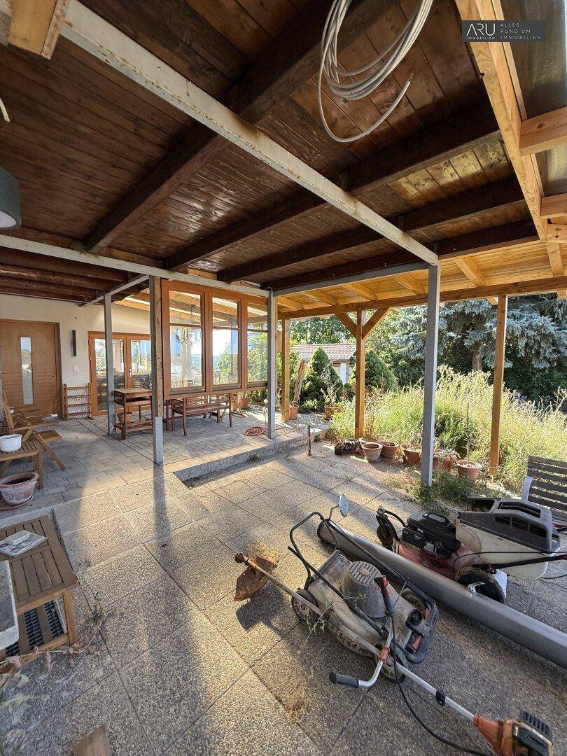 Überdachter Terrassenbereich mit Holzdach und Blick ins Grüne, derzeit im Umbau.