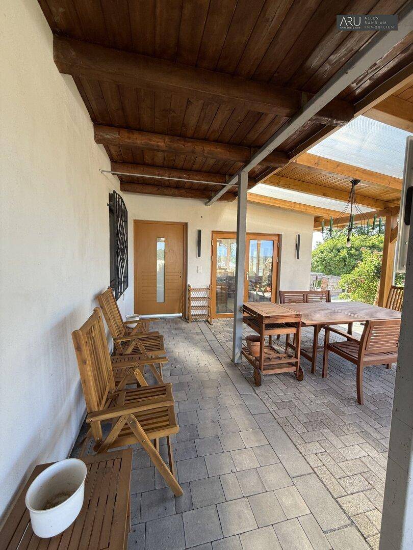 Überdachte Terrasse mit Holzdach, Esstisch und Stühlen für entspannte Stunden im Freien.