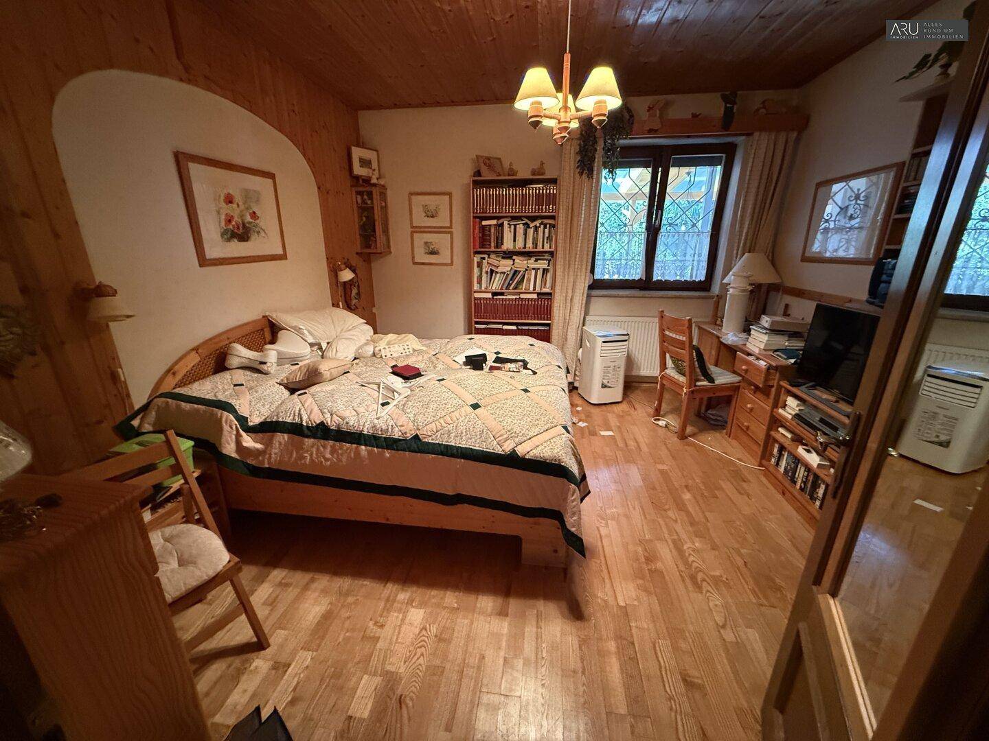Gemütliches Schlafzimmer mit Holzboden, Holzdecke und traditioneller Einrichtung.