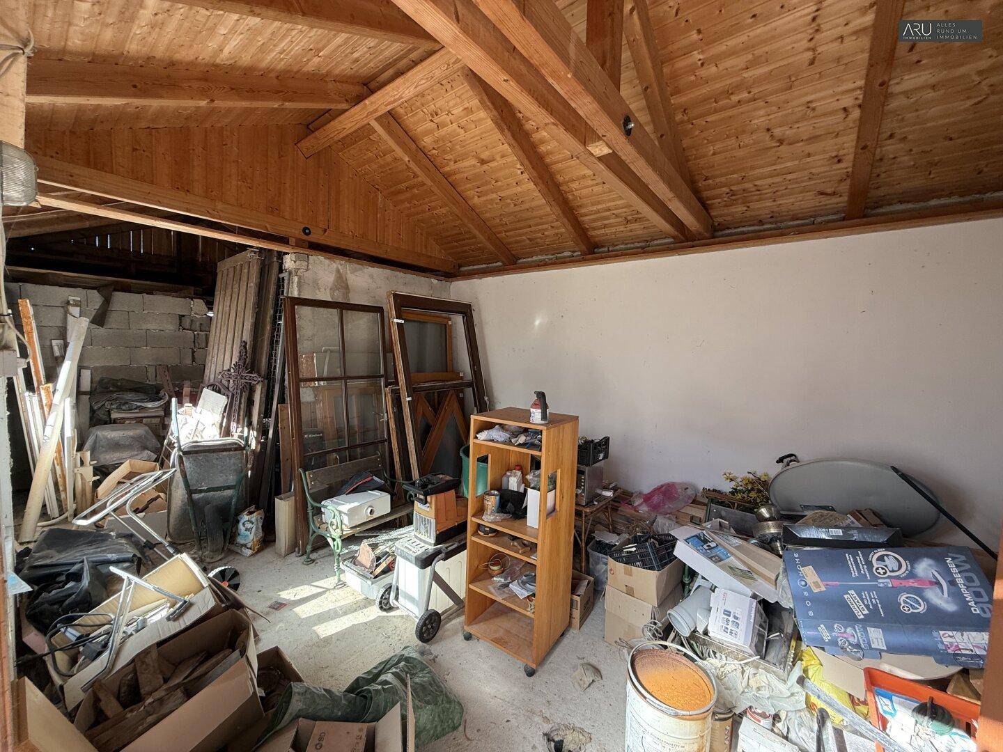 Unaufgeräumter Abstellraum mit Holzdachstuhl und Baumaterialien.