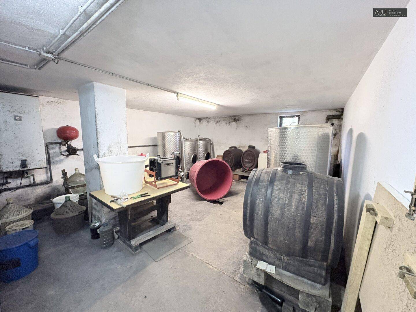 Großer Weinkeller mit Fässern und Edelstahltanks zur Weinproduktion und Lagerung.