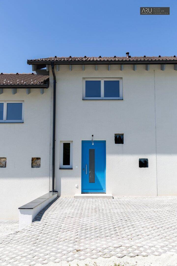 Nahaufnahme der modernen Fassade eines Reihenhauses mit leuchtend blauer Eingangstür.