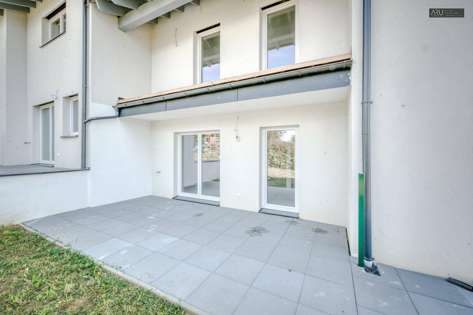 Gepflasterte Terrasse im Erdgeschoss mit Zugang zum Garten und großen Schiebetüren.