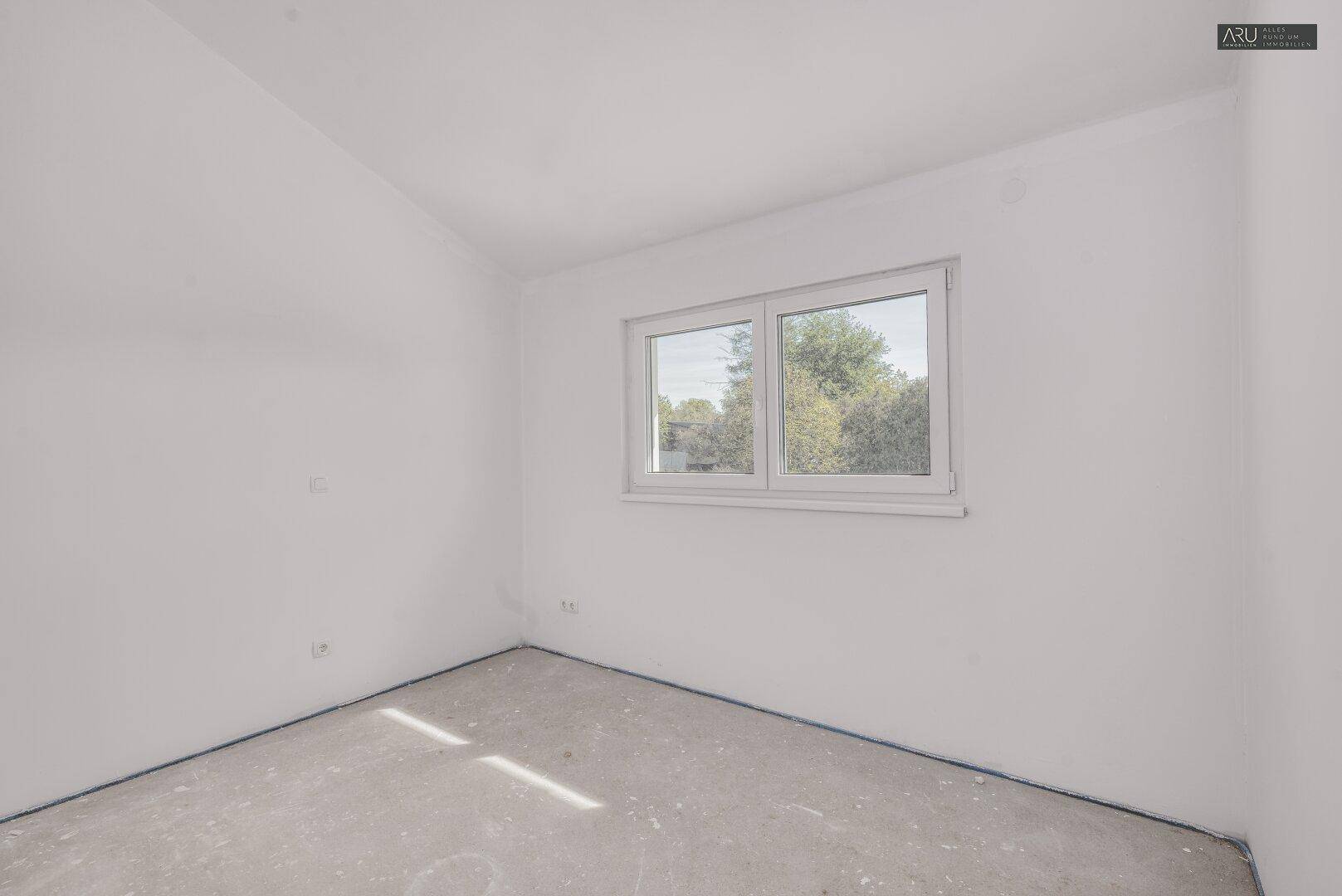 Helles, unfertiges Zimmer mit Fenster und Blick ins Grüne, ideal als Schlaf- oder Arbeitszimmer.