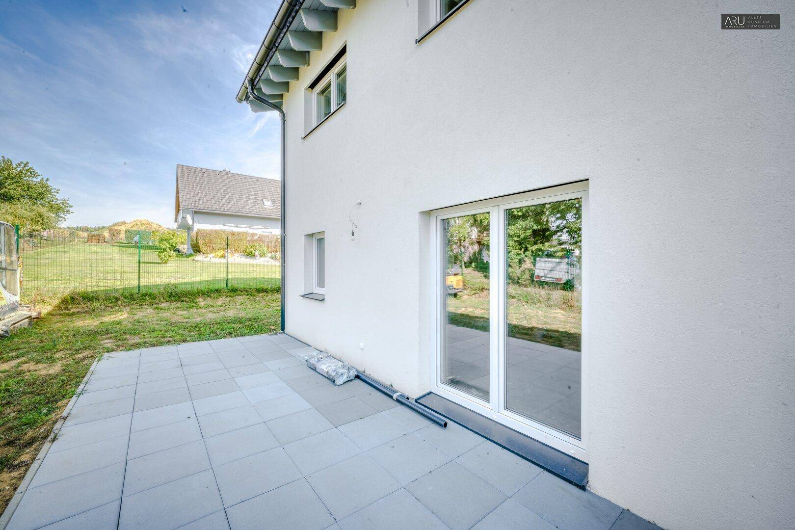 Gepflasterte Terrasse am Haus mit Zugang zum Garten und Schiebetür.