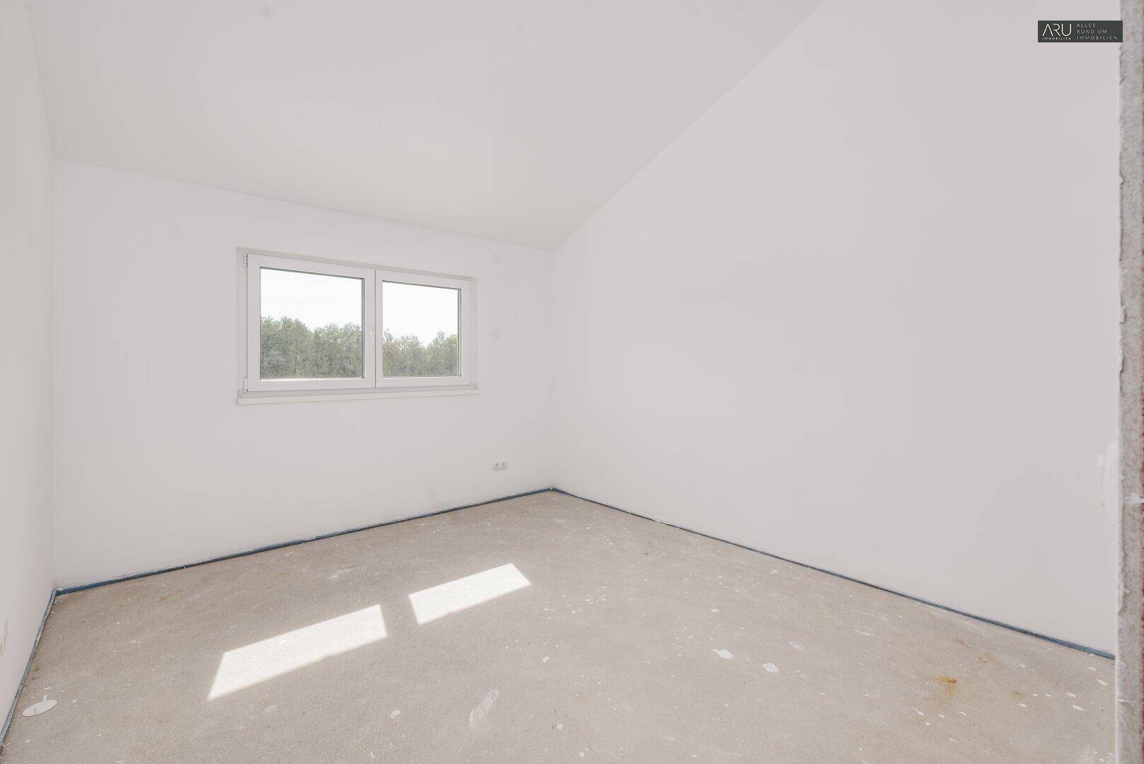 Unfertiges Schlafzimmer im Obergeschoss mit einem Fenster und viel Tageslicht.