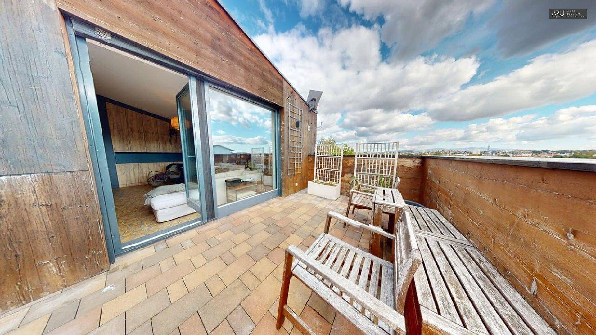 Geräumige Dachterrasse mit Holzboden und weitem Blick über die Umgebung.
