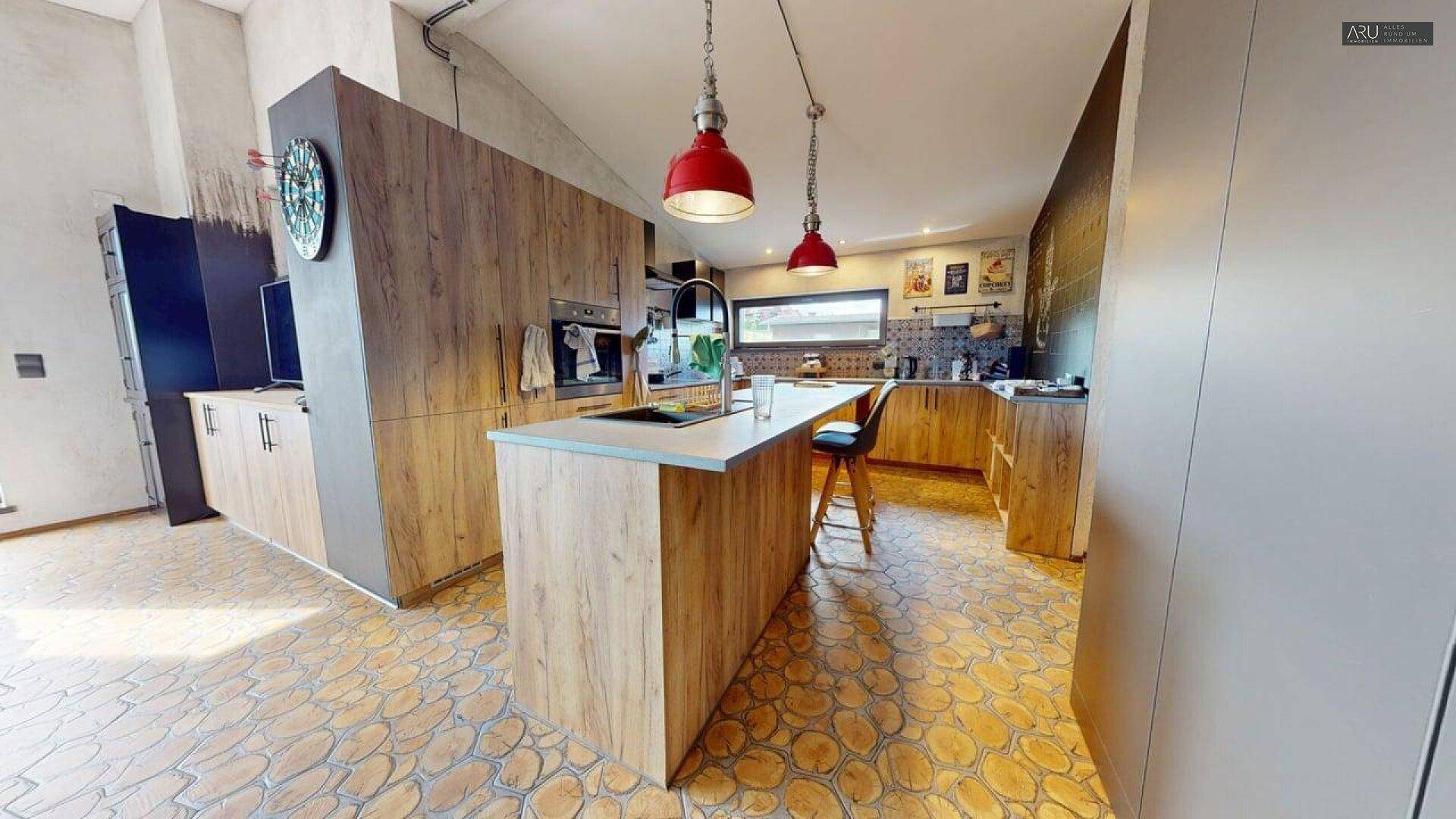 Moderne Holzküche mit Kücheninsel, roten Hängelampen und einzigartigem Holzboden.