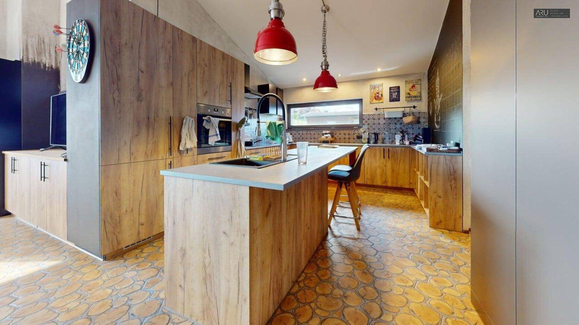 Moderne Holzküche mit Kücheninsel, roten Hängelampen und einzigartigem Holzboden.