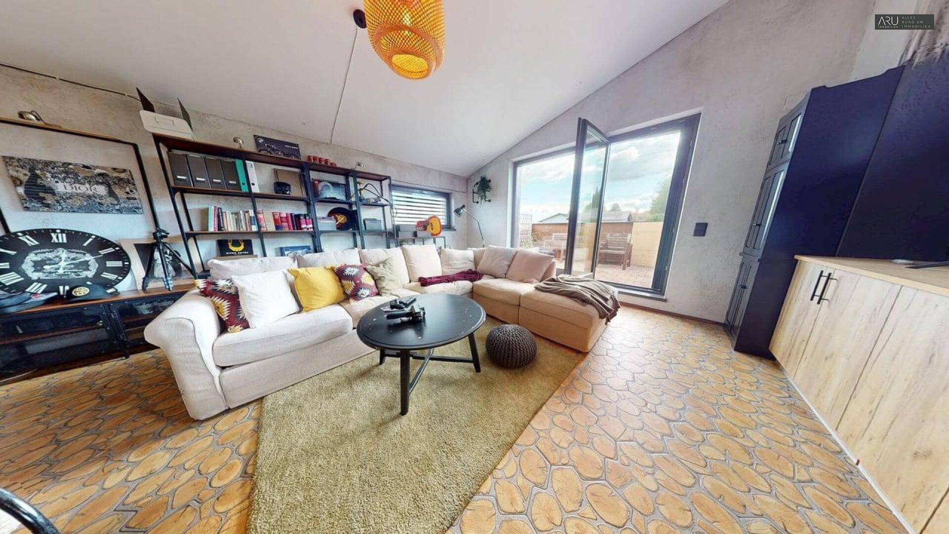 Gemütliches Wohnzimmer mit großem Sofa, Holzboden und Zugang zur Terrasse.