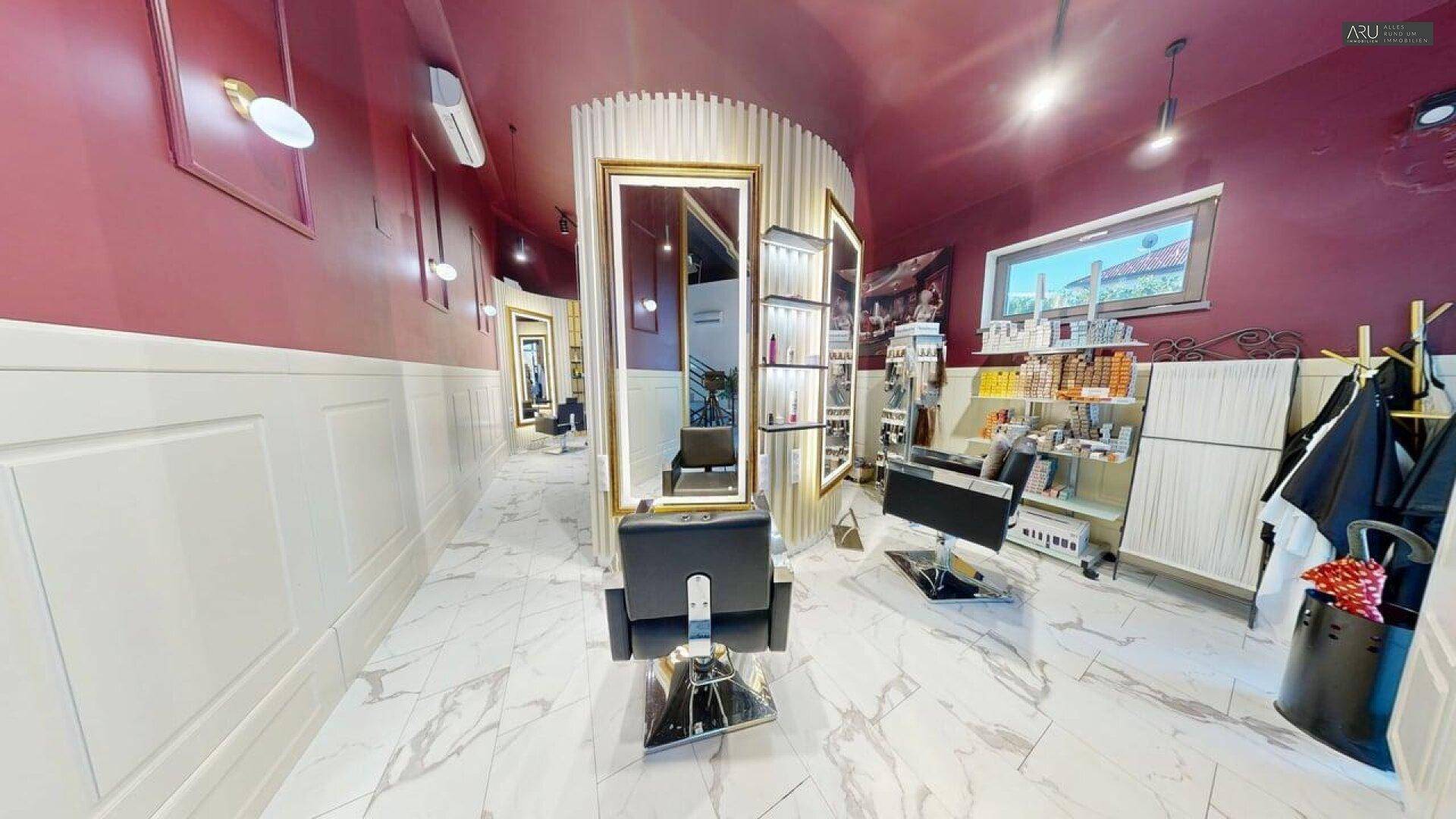 Moderner Friseursalon mit großen Spiegeln, Marmorboden und stilvoller Einrichtung in Rot- und Weißtönen.