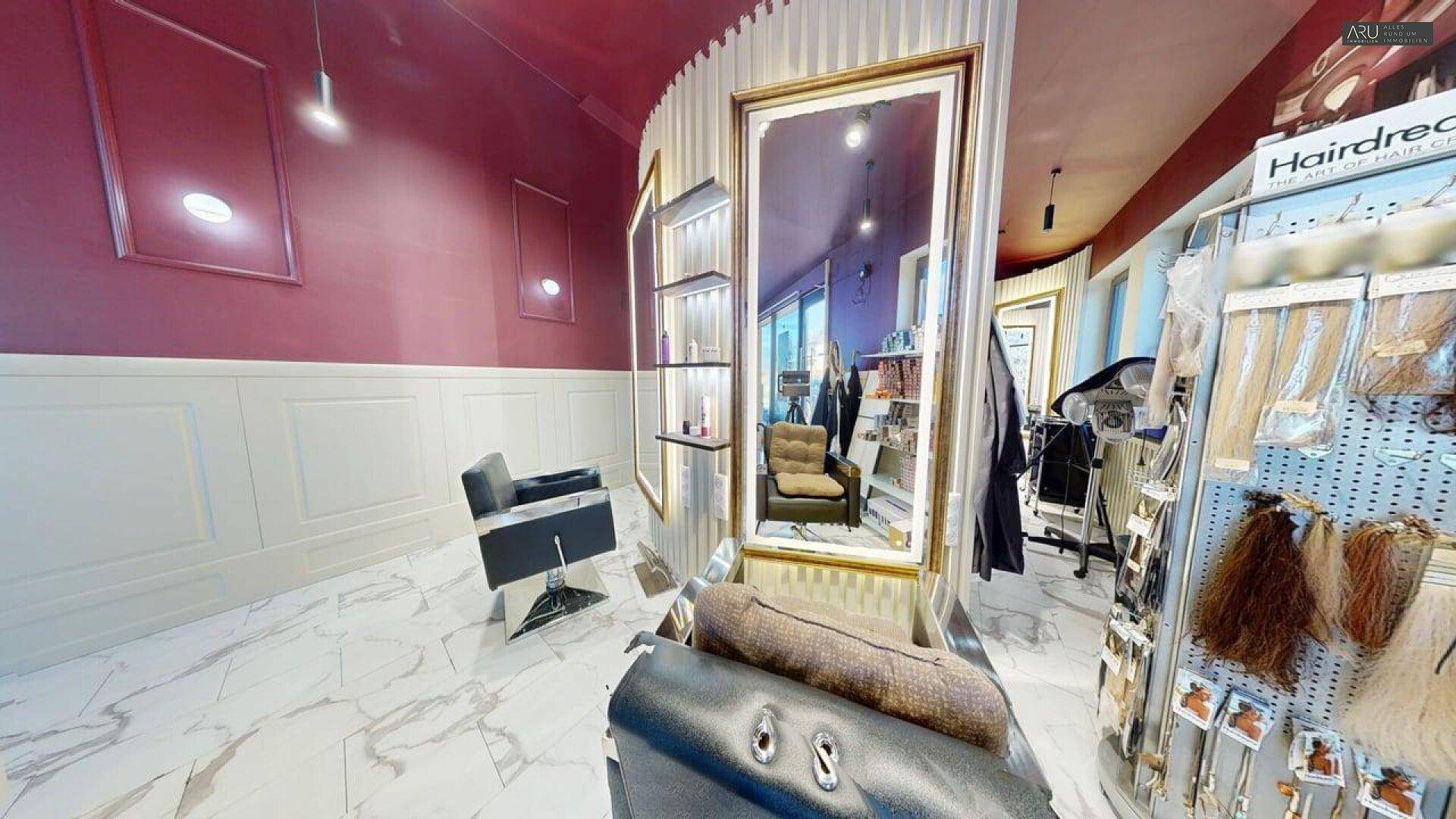 Innenansicht eines Friseursalons mit eleganten Spiegeln, Marmorboden und bequemen Stühlen für Kunden.