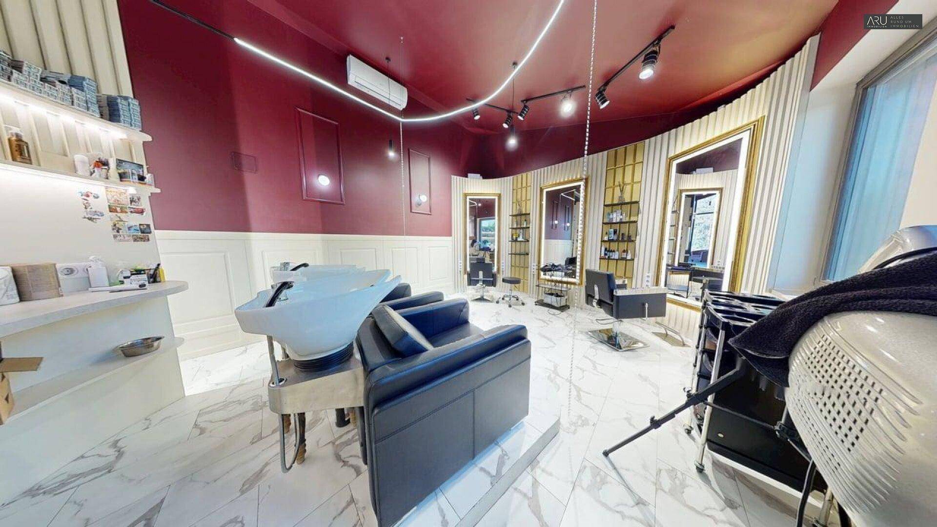 Waschbereich eines modernen Friseursalons mit bequemen Stühlen und Marmorboden unter stilvoller Beleuchtung.