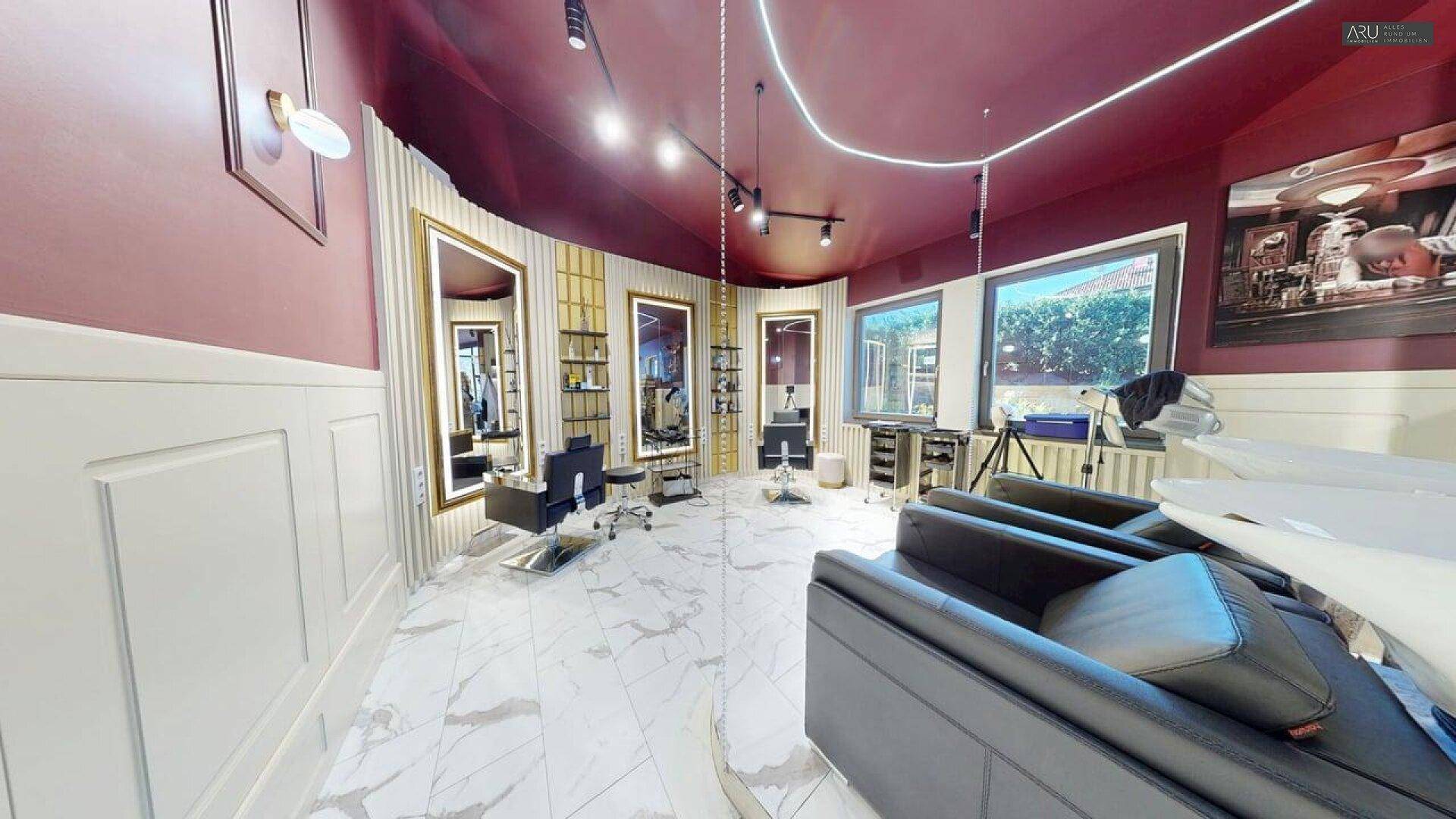 Geräumiger Friseursalon mit mehreren Styling-Stationen, großen Fenstern und Marmorboden.