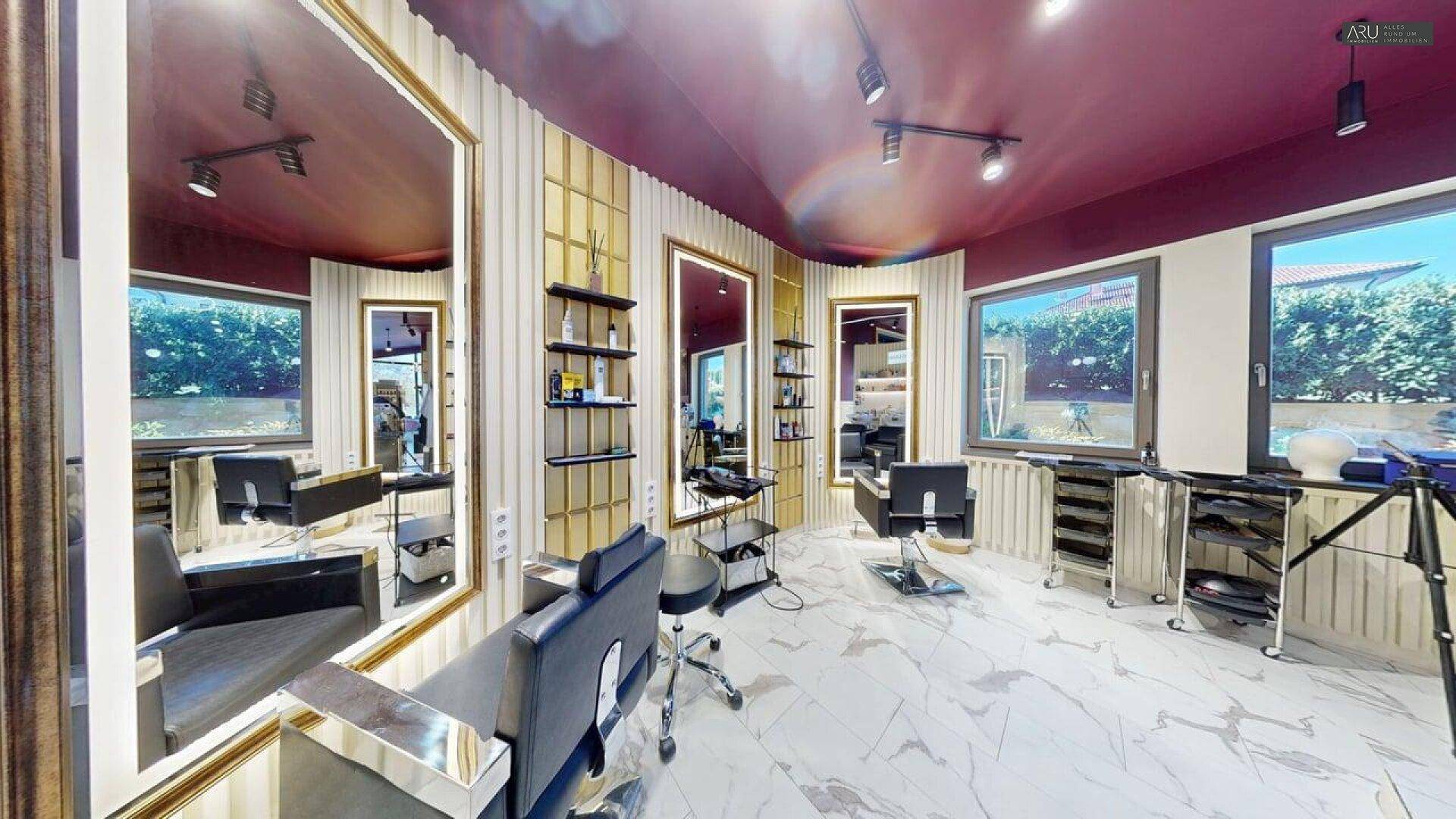 Friseursalon mit mehreren Styling-Stationen, großen Spiegeln und Blick nach draußen.