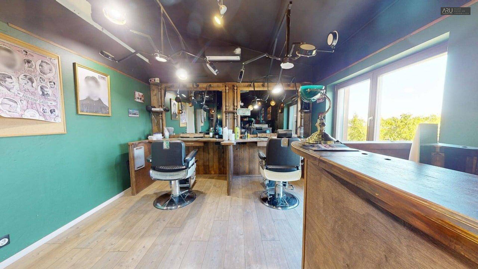 Barbershop im Vintage-Stil mit Holzfußboden, grünen Wänden und klassischen Friseurstühlen.