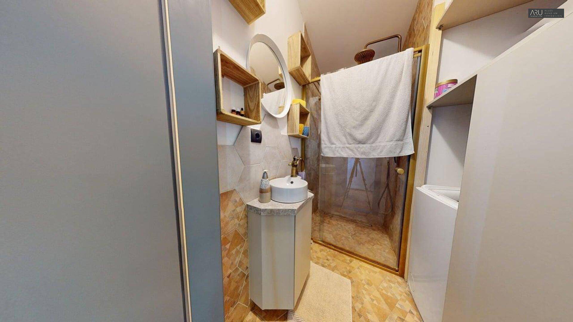 Modernes Badezimmer mit rundem Spiegel, Holzregalen und Duschkabine.