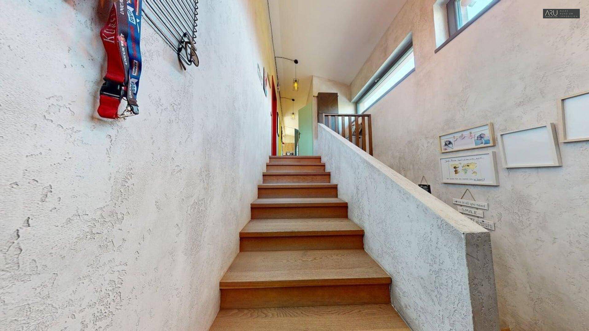 Treppenaufgang mit Holzstufen und strukturierten Wänden, führt zu weiteren Räumen.
