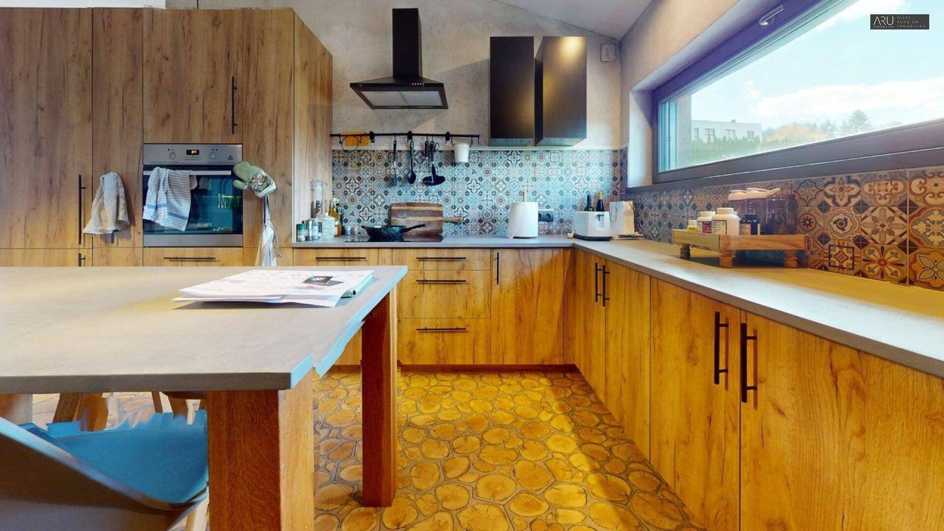 Moderne Holzküche mit integrierten Geräten, gemusterten Fliesen und großem Fenster.
