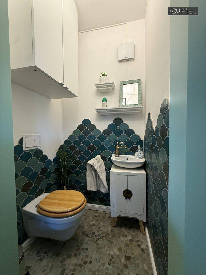 Gäste-WC mit auffälligen blauen Schuppenfliesen und modernem Waschbecken.