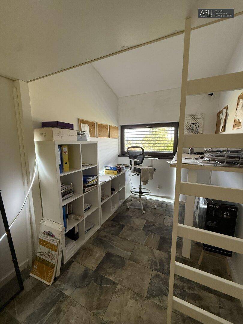 Helles Arbeitszimmer mit Schreibtisch, Regalen und Fenster, ideal für Home-Office.